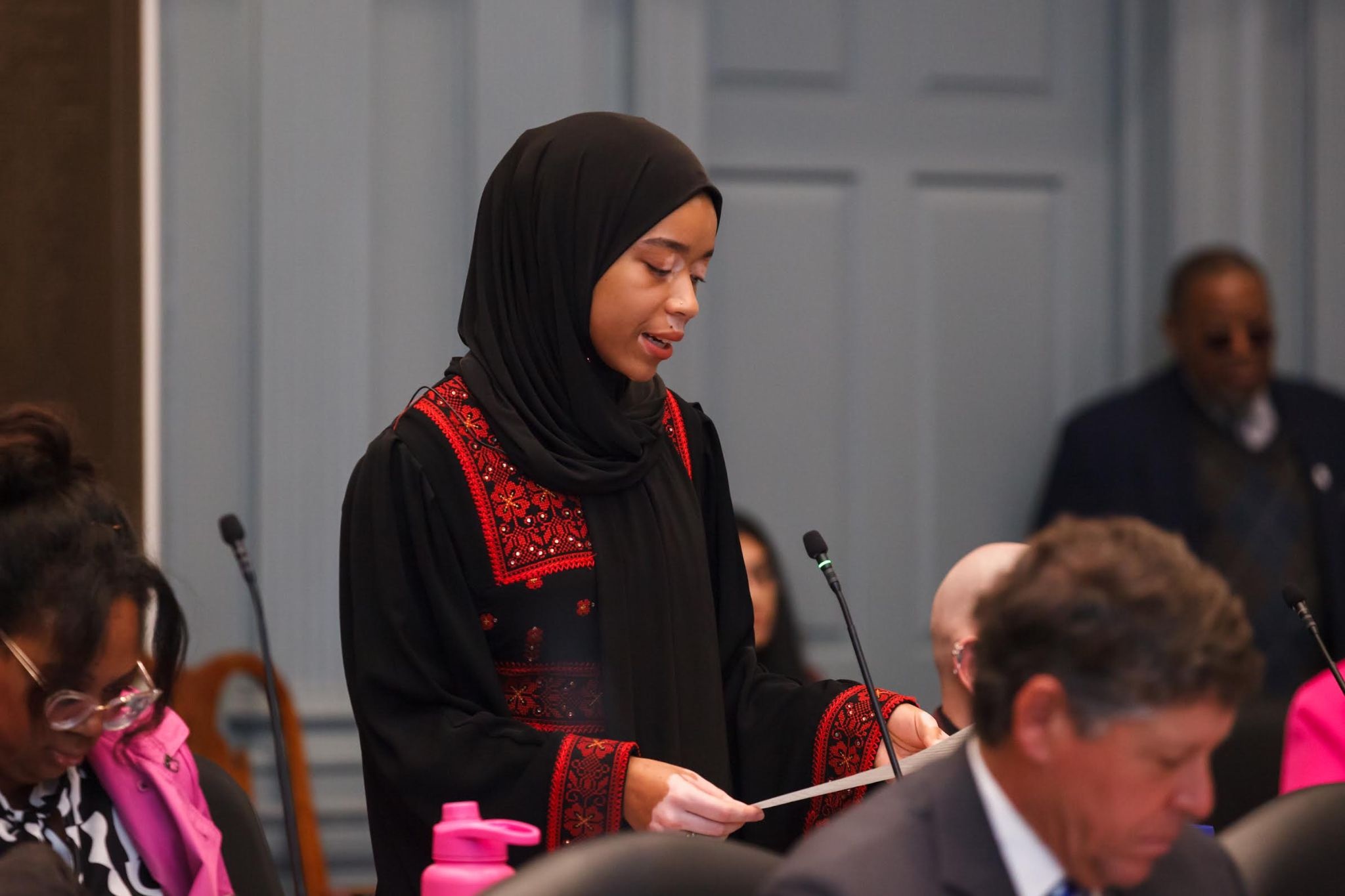 a woman standing giving a speech in a room of local Delaware politicians