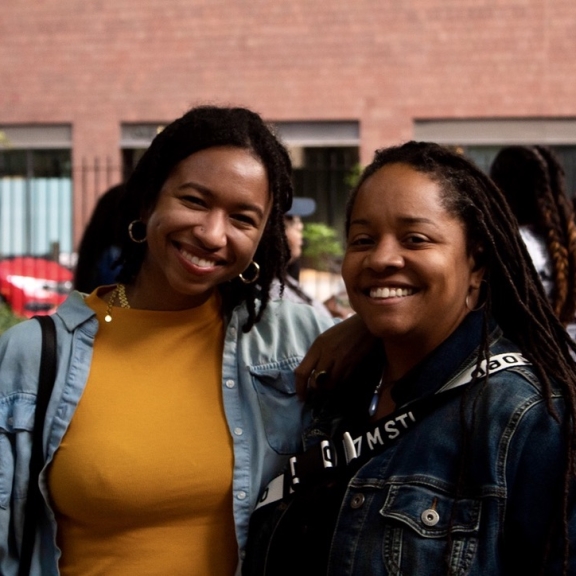 two people standing next to each other looking at the camera and smiling