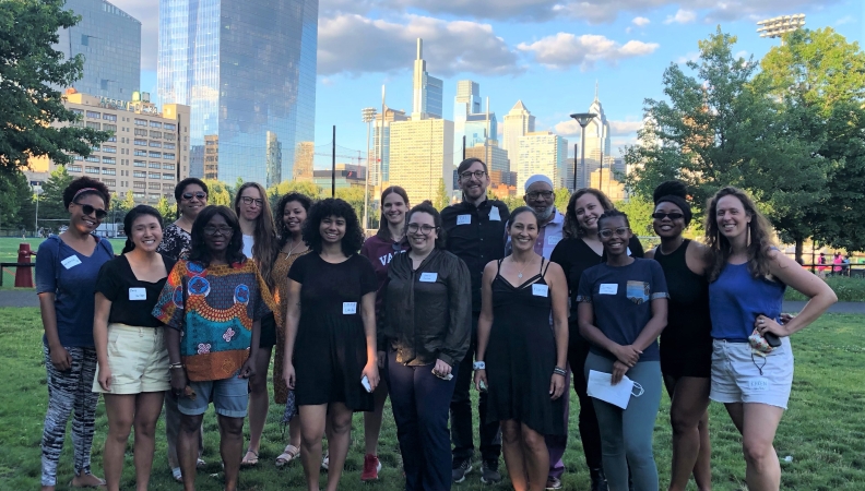 Sixteen people posing for a picture in a park