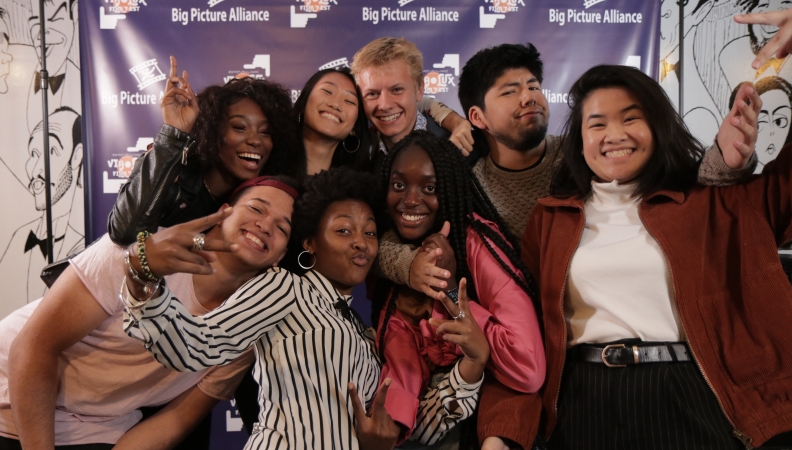 Eight people posing for a picture in front of a Big Picture Alliance background