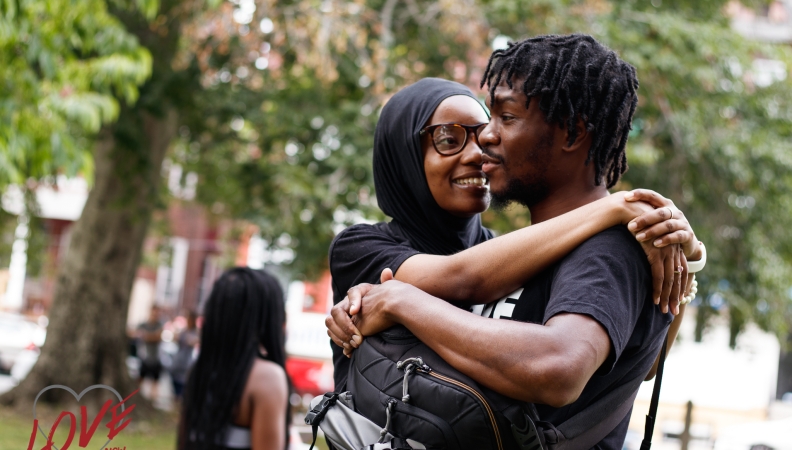 a woman hugging a man while the man carries a backpack