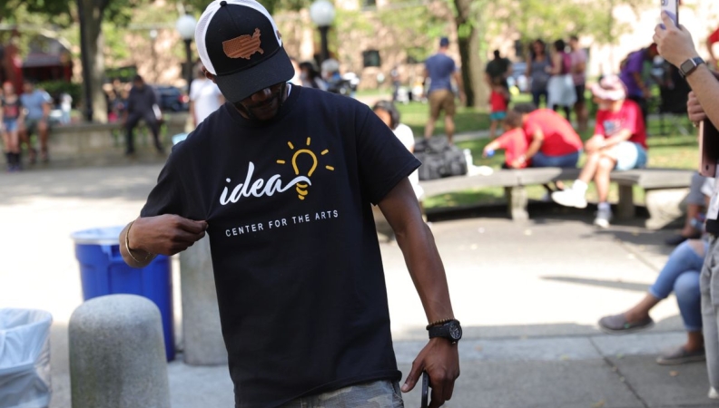 A person looking down and holding their IDEA Center for the Arts t-shirt