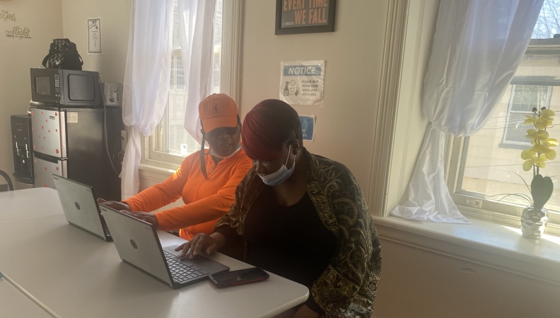 Two people sitting together working on laptops