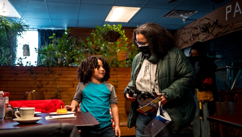 filmmaker holding film equipment in one hand and talking with a child actor standing to their left