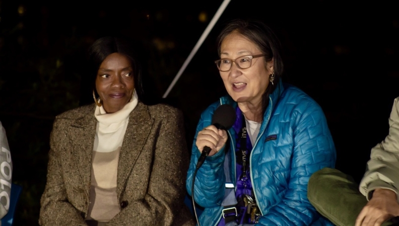 a woman speaks into microphone during a film panel conversation with another woman looking at her and listening intently