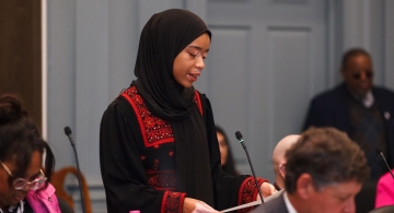 a woman wearing a hijab speaks in a congress of local Delaware politicians