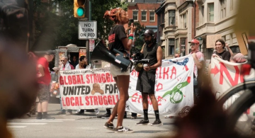 a woman holds a megaphone at a pro-Palestine rally while a man films her 