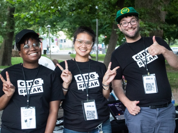 Three people posing; two giving peace signs, one giving a thumbs up