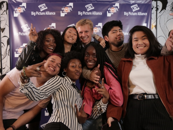 Eight people posing for a picture in front of a Big Picture Alliance background