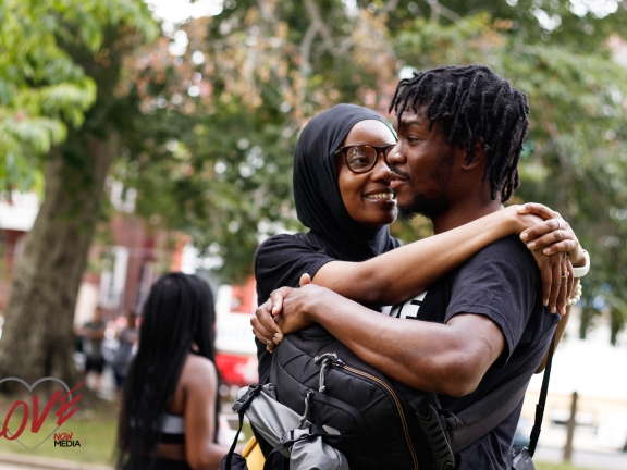 a woman hugging a man while the man carries a backpack