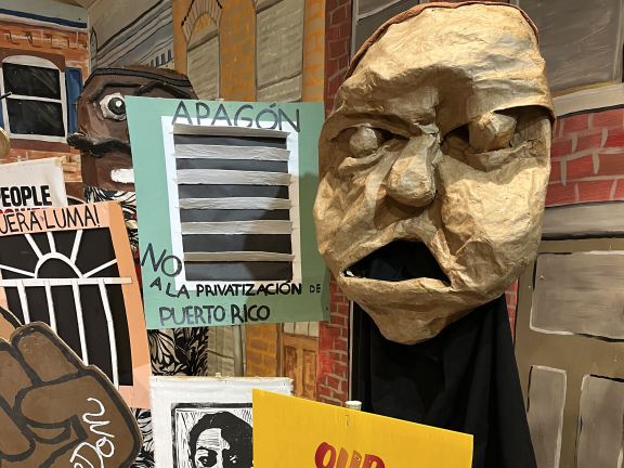 A Spiral Q puppet show display that reads 'our community is not for sale'