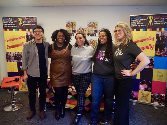 a group of 5 people photographed in front of banners that read commemorating community