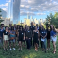 Sixteen people posing for a picture in a park