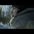 Profile of a person standing outside on a snowy day wearing a scarf and hat