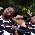 Two people in black and white costumes with both hands raised and heads tilted to the left