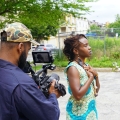 a man filming a woman with her eyes closed and her hands on her chest