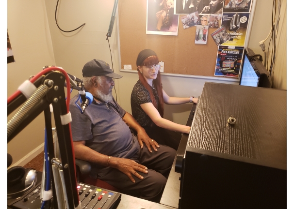 two people seated in a studio looking at a computer screen