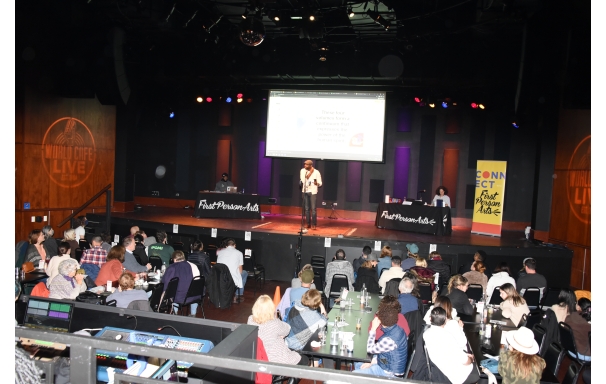 A person speaks to a crowd at the World Cafe Live