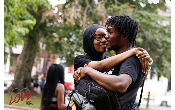 a woman hugging a man while the man carries a backpack