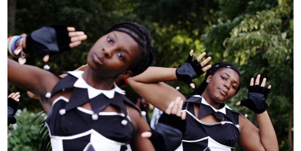 Two people in black and white costumes with both hands raised and heads tilted to the left