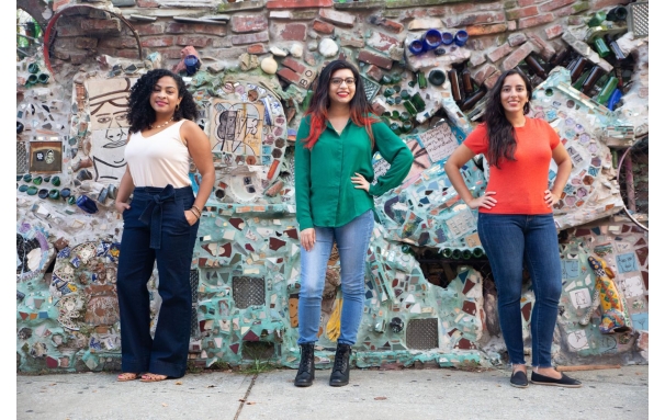 Three people standing in front of a mosaic wall