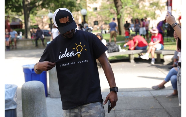 A person looking down and holding their IDEA Center for the Arts t-shirt