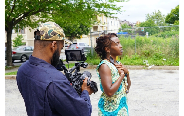 a man filming a woman with her eyes closed and her hands on her chest