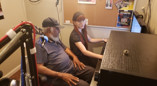 two people seated in a studio looking at a computer screen