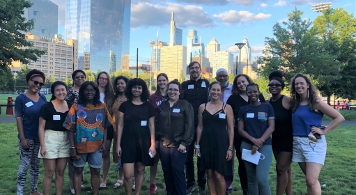 Sixteen people posing for a picture in a park