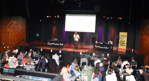 A person speaks to a crowd at the World Cafe Live