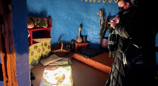Two people inside a small room with blue walls taking pictures of the art
