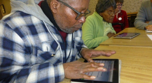 A group of older people seated at a table using tablets