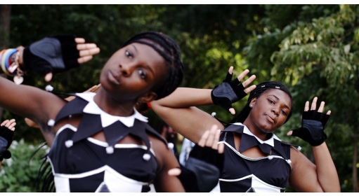 Two people in black and white costumes with both hands raised and heads tilted to the left
