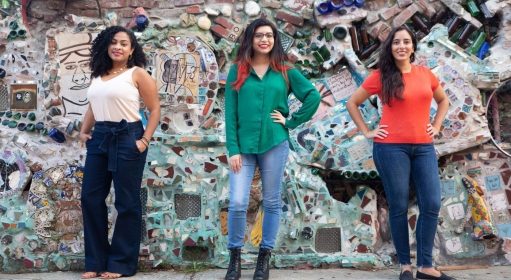 Three people standing in front of a mosaic wall