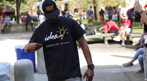 A person looking down and holding their IDEA Center for the Arts t-shirt