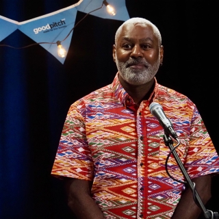 man standing behind a microphone looks out to an audience